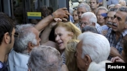A pensioner (C) reacts as she tries to enter a National Bank branch to receive part of her pension at the city of Iraklio in the island of Crete, Greece July 9, 2015. 