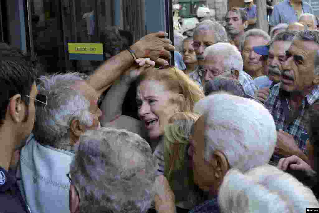 A pensioner (C) reacts as she tries to enter a National Bank branch to receive part of her pension in the city of Iraklio on the island of Crete, Greece.