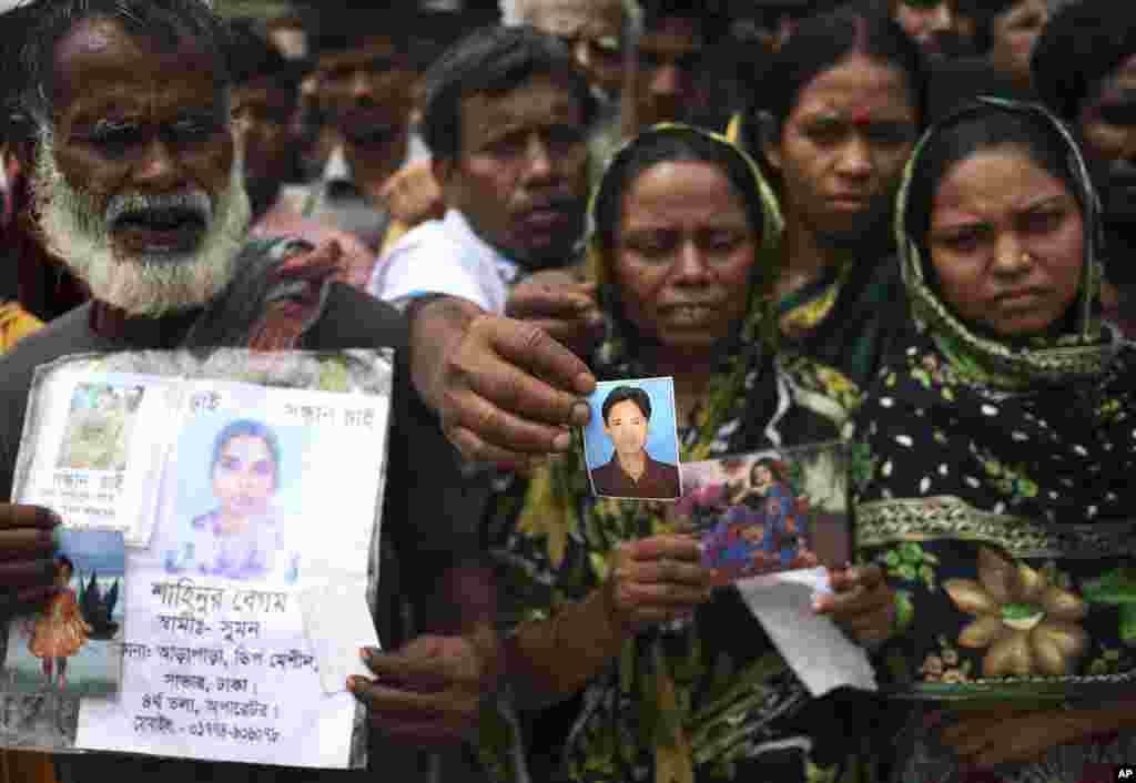 A man holds out a picture of his missing relative on Monday April 29, 2013 in Savar, near Dhaka, Bangladesh. 