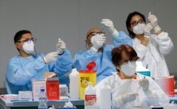 FILE - Health workers prepare doses of the Pfizer-BioNTech COVID-19 vaccine at a coronavirus disease (COVID-19) vaccination center in Naples, Italy, Jan. 8, 2021.