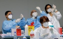 FILE - Health workers prepare doses of the Pfizer-BioNTech COVID-19 vaccine at a vaccination center in Naples, Italy, Jan. 8, 2021.