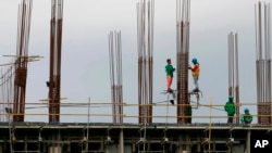 FILE - Construction workers stand on scaffolding around metal rods of a new pillar as they add more floors to a building project in suburban Paranaque city, south of Manila, Philippines, Jan. 26, 2017. 