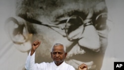 Veteran Indian social activist Anna Hazare raises his fist in front of a portrait of Mahatma Gandhi at Ramlila grounds in New Delhi, Aug. 19, 2011.