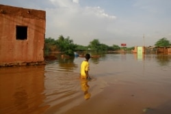FILE - A boy wades through a flooded street in the area of al-Qamayir in the capital's twin city of Omdurman, Sudan, Aug. 26, 2020.