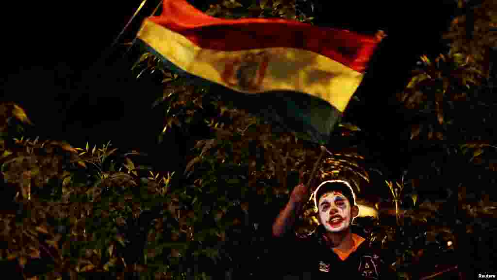 Un manifestante con el rostro pintado de modo que recuerda al Jóker agita la bandera boliviana durante la manifestación.