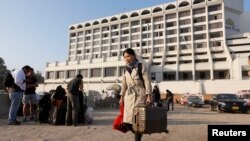 A foreign guest carrying her belongings as she leaves after a fire erupted in a hotel early morning in Karachi, Pakistan, Dec. 5, 2016.