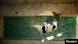 Palestinian students look inside a classroom that witnesses said was shelled by Israel during its offensive, on the first day of the new school year east of Gaza City September 14, 2014.