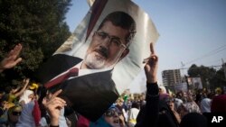 Umupfasoni afise isanamu ya Mohamwed Morsi yahoze ari prezida wa Misiri