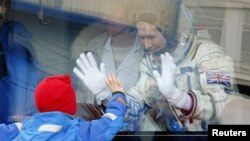 British astronaut Tim Peake, a member of the main crew of the International Space Station, waves to his children from a bus prior the launch of Soyuz TMA-19M space ship, at the Russian leased Baikonur cosmodrome, Kazakhstan, Dec. 15, 2015.