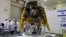 Israeli scientists stand next to an unmanned spacecraft which an Israeli team plans to launch into space at the end of the year and to land it on the moon next year, in Yahud, Israel, July 10, 2018.