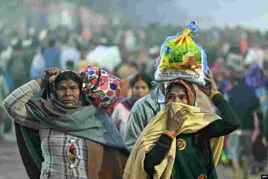 Hindu pilgrims arrive with their belongings to take a holy dip in the sacred waters of Sangam, the confluence of Ganges, Yamuna and mythical Saraswati rivers, during the Maha Kumbh Mela festival in Prayagraj on Jan. 13, 2025.