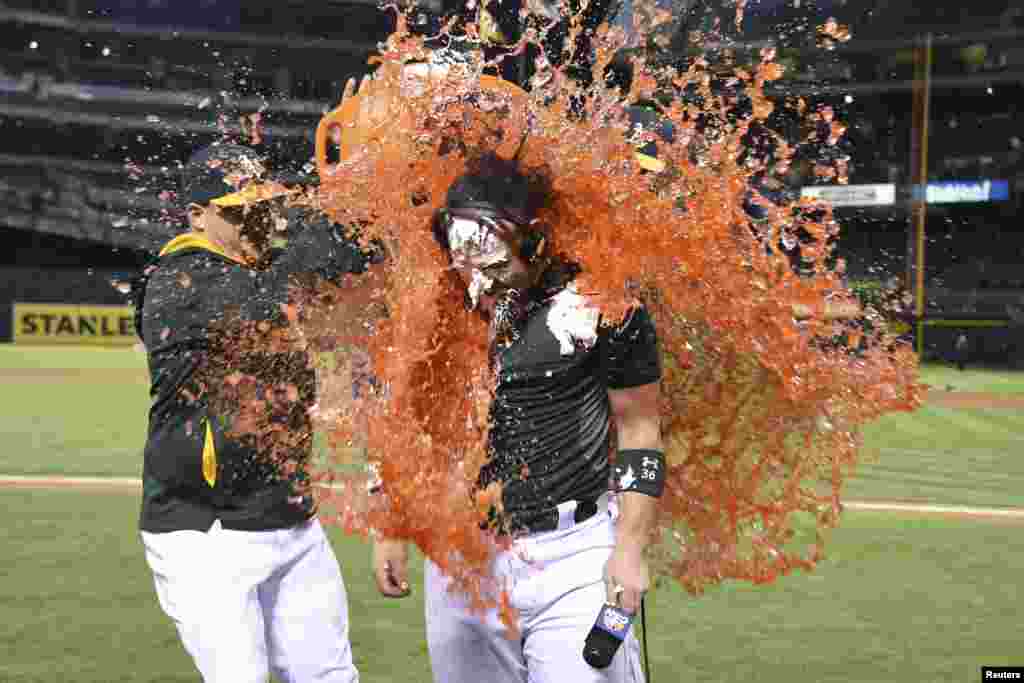 Oakland Athletics first baseman Stephen Vogt (21, left) dumps Gatorade on catcher Derek Norris (36, right) after Norris hit the game-winning RBI-single during the 10th inning against the Tampa Bay Rays at O.co Coliseum, Oakland, California, USA, Aug. 4, 2014. (Credit: Kyle Terada-USA TODAY Sports)