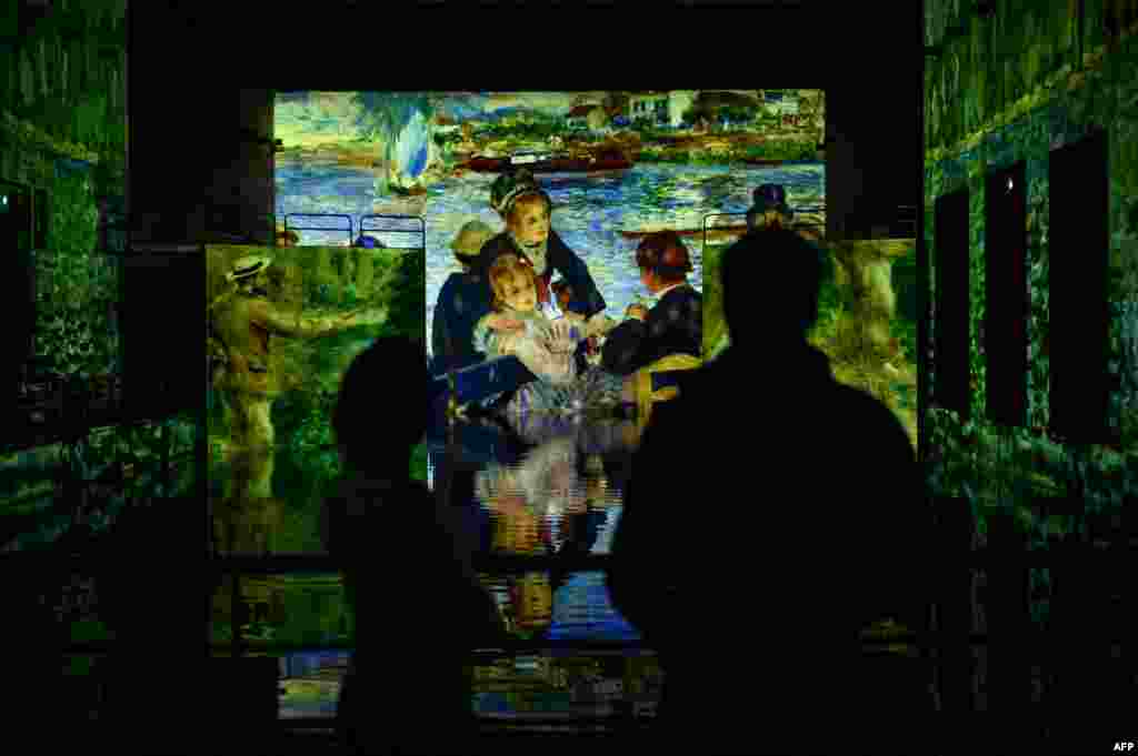 Journalists watch projections of paintings during a press visit of the digital exhibition entitled &quot;Monet, Renoir, and Chagall: Journeys Around the Mediterranean&quot; at the &quot;Bassin des Lumieres&quot; in a former German WWII submarine base in Bordeaux, France.