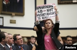 A protester holds a sign as U.S. Defense Secretary Ash Carter and U.S. Joint Chiefs Chairman General Martin Dempsey (unseen) testify before a House Armed Services Committee hearing on Capitol Hill in Washington, June 17, 2015.