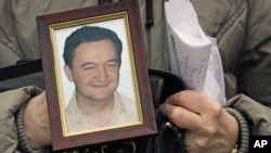 A November 2009 photo shows a portrait of Russian lawyer Sergei Magnitsky who died in jail, held by his mother Nataliya Magnitskaya in Moscow.