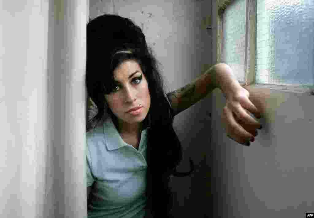 In this 2007 file photo, British singer Amy Winehouse poses for photographs after being interviewed by The Associated Press at a studio in north London. The singer was found dead at her home in London on Saturday, July 23. She was 27 years old. (AP Photo/
