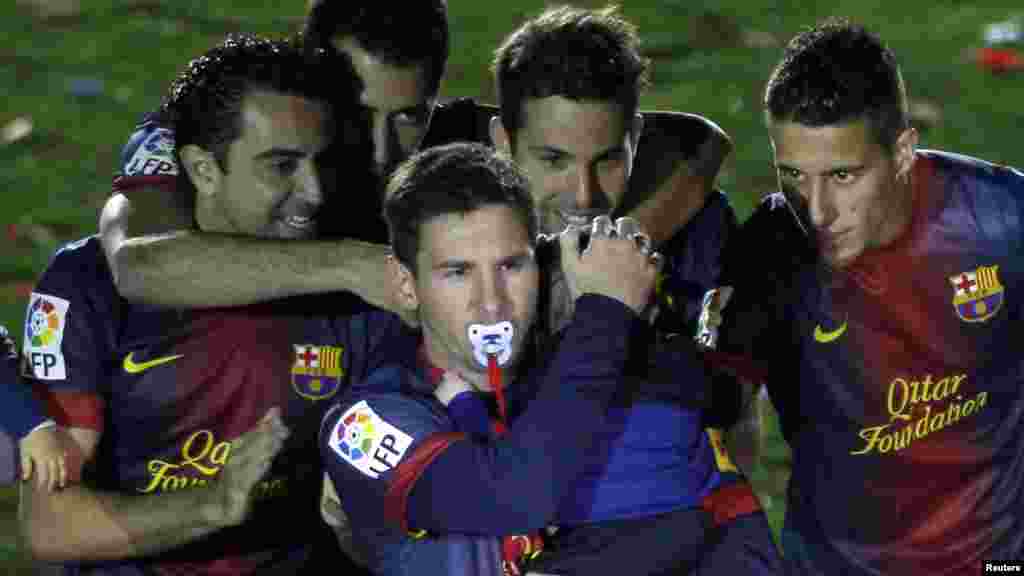 Barcelona's Lionel Messi, with a dummy in his mouth, carries his son Thiago near his team mates during the Spanish league first division trophy celebrations in Barcelona May 19, 2013.