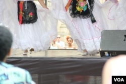 One of the younger members of Baltimore's "Bailes de Mi Tierra" Mexican folk dance group watches the older girls perform the first dance at the start of the One Journey Festival in support of refugees, Washington, June 2, 2018. (V. Macchi/VOA)