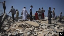 In this photo taken on a government-organized tour, Libyan men stand on top of the remains of a medical clinic that was destroyed during a NATO airstrike early Monday morning, in the town of Zlitan, roughly 160 km (99 miles) east of Tripoli, Libya, Monday