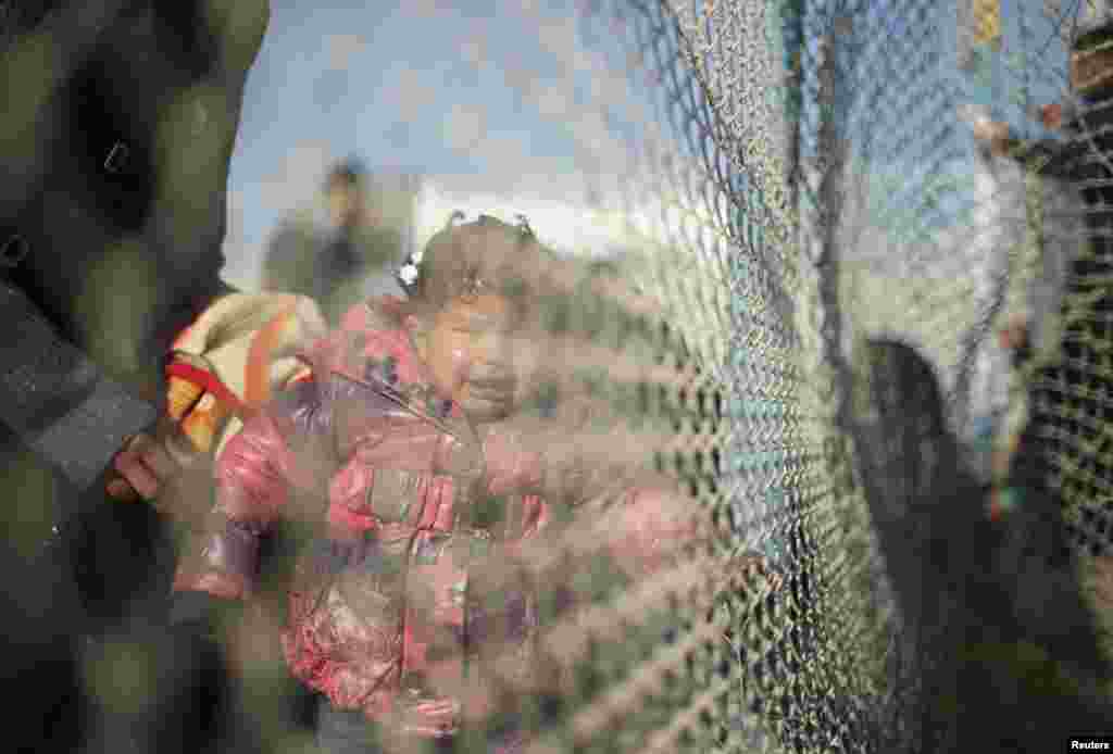 Một bé gái người Palestine, hy vọng vượt biên giới vào Ai Cập cùng với gia đình, khóc khi đứng đằng sau một hàng rào tại cửa khẩu biên giới Rafah giữa Ai Cập và Dải Gaza ở miền nam.