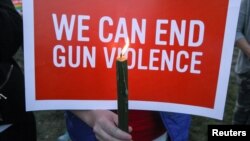 Mourners hold signs during a solidarity vigil in memory of victims of the Las Vegas music festival mass killing, in Newtown, Connecticut, site of the 2012 Sandy Hook school shooting, Oct. 4, 2017. 