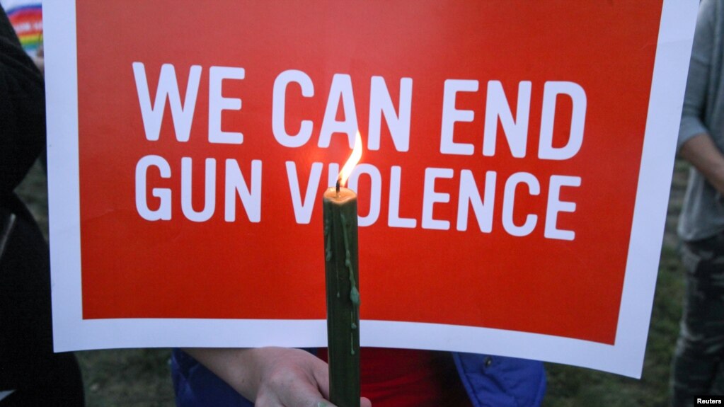 FILE - Mourners hold signs during a solidarity vigil in memory of victims of the Las Vegas music festival mass killing, in Newtown, Connecticut, site of the 2012 Sandy Hook school shooting, Oct. 4, 2017.