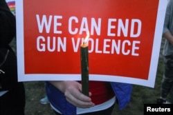 Mourners hold signs during a solidarity vigil in memory of victims of the Las Vegas music festival mass killing, in Newtown, Connecticut, site of the 2012 Sandy Hook school shooting, Oct. 4, 2017.