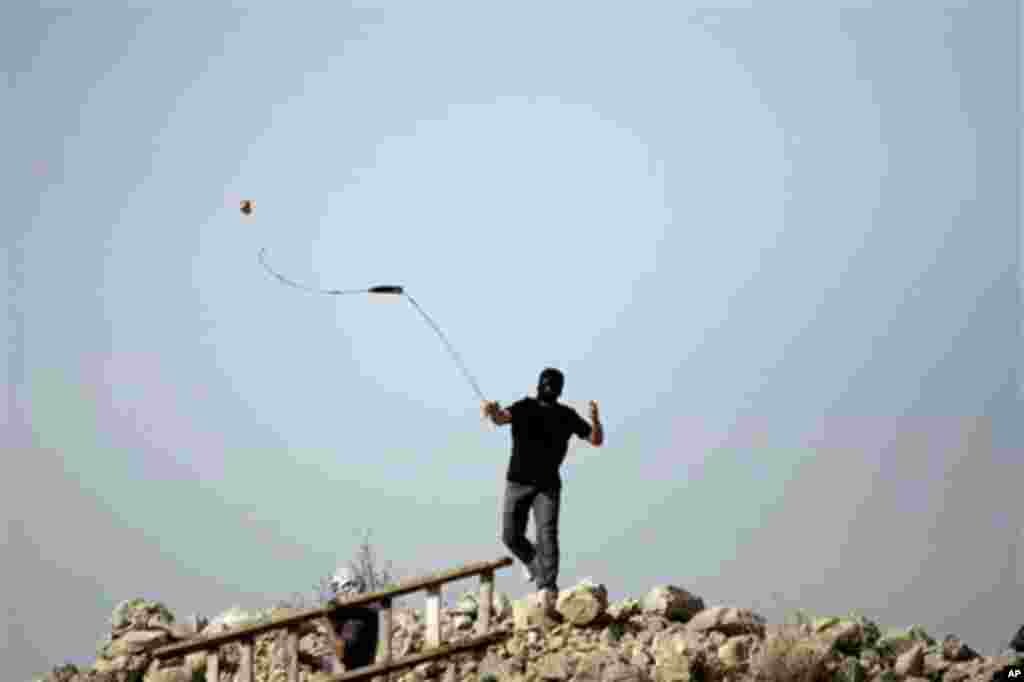 January 14: A Palestinian protester uses a slignshot to hurl a stone at Israeli troops, during a protest against Israel's separation barrier in the West Bank village of Nilin near Ramallah. (AP Photo/Majdi Mohammed)