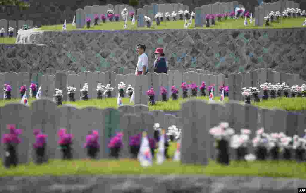 People walk past gravestones of South Korean soldiers killed in the 1950-53 Korean War, on the Korean Memorial Day at the National Cemetery in Seoul, South Korea.