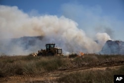 An Israeli tractor extinguishes a fire started by a kite with attached burning cloth launched by Palestinians from Gaza, on the Israel and Gaza border, June 20, 2018.