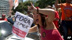 ຜູ້ປະທ້ວງຄົນໜຶ່ງ ຖືປ້າຍ ທີ່ອ່ານວ່າ holds a sign that reads “Temer ຈົ່ງອອກໄປ” ໃນລະຫວ່າງ ການປະທ້ວງຕໍ່ຕ້ານປະທານາທິບໍດີ ຂອງ ບຣາຊິລ ທ່ານ Michel Temer ຢູ່ທີ່ ຊາຍຫາດ Copacabana, ໃນ Rio de Janeiro, ບຣາຊີລ, ວັນອາທິດ ທີ 4 ກັນຍາ 2016.