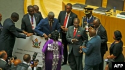 Zimbabwe's President, Robert Mugabe (C) gives a $1 million cheque to the African Union Foundation during the 29th African Union Summit in Addis Ababa, Ethiopia, July 3, 2017. 