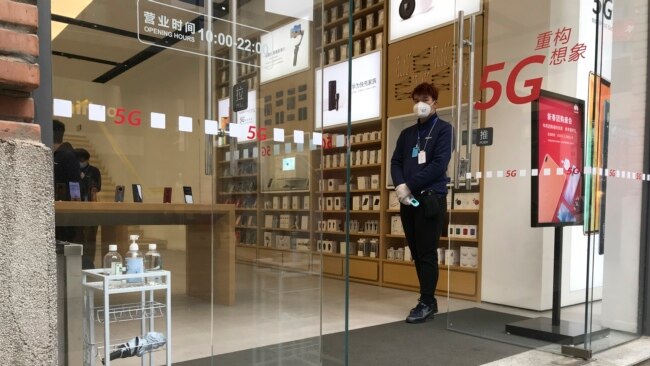 武汉周一解封,一家重新开门的商店的营业员在门口等候顾客。(2020年3月30日)