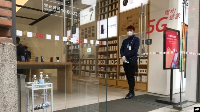武汉周一解封,一家重新开门的商店的营业员在门口等候顾客。(2020年3月30日)