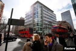 FILE - People walk past the building housing the offices of Cambridge Analytica in central London, Britain, March 20, 2018.