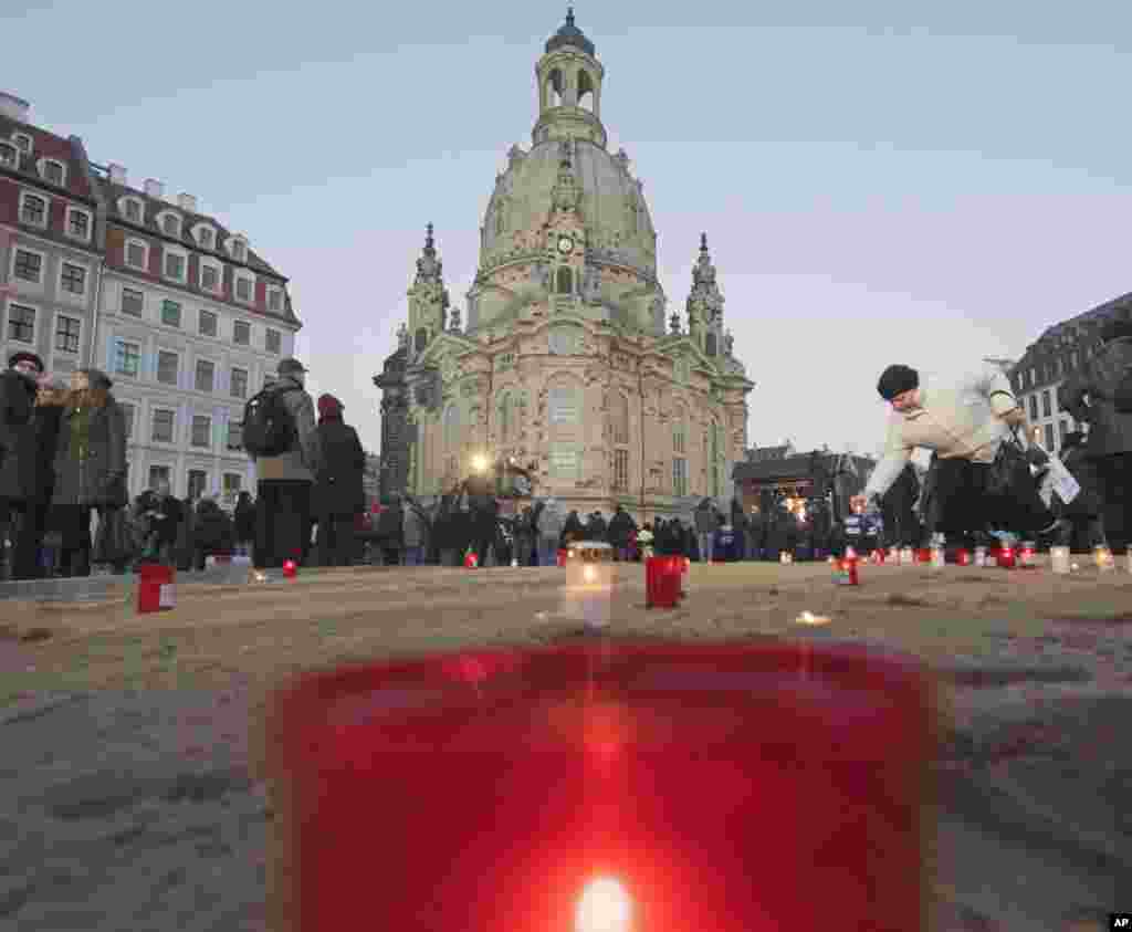 Một người phụ nữ thắp một ngọn nến đặt phía trước nhà thờ Frauenkirche (Nhà thờ Đức Mẹ) kỷ niệm 70 năm vụ ném bom chết người của quân đồng minh ở thành phố Dresden trong Thế chiến thứ hai, Dresden, Đông Đức. Máy bay ném bom của Anh và Mỹ đã tàn phá trung tâm thành phố hàng trăm năm tuổi mang phong cách kiến trúc baroque.