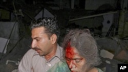 A Pakistan man helps an injured woman from the site of a deadly car bomb explosion in Karachi, Pakistan, 11 Nov. 2010.