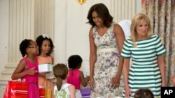 Ibu Negara Michelle Obama dan Jill Biden bersama anak-anak yang sedang membuat prakarya untuk diberikan kepada ibu mereka dalam acara tahunan Hari Ibu untuk menghormati para ibu yang terlibat dengan militer di Gedung Putih, Washington, Jumat, 8 Mei 2015. (AP Photo/Carolyn Kaster)