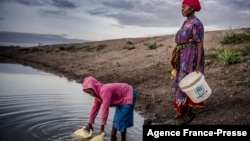 FILE: Martha Kasafi (right) and her daughter, both refugees from Democratic Republic of Congo, collect water for their vegetable crops at a water pan in Kalobeyei settlement for refugees in Turkana County, Kenya on Oct. 2, 2019.