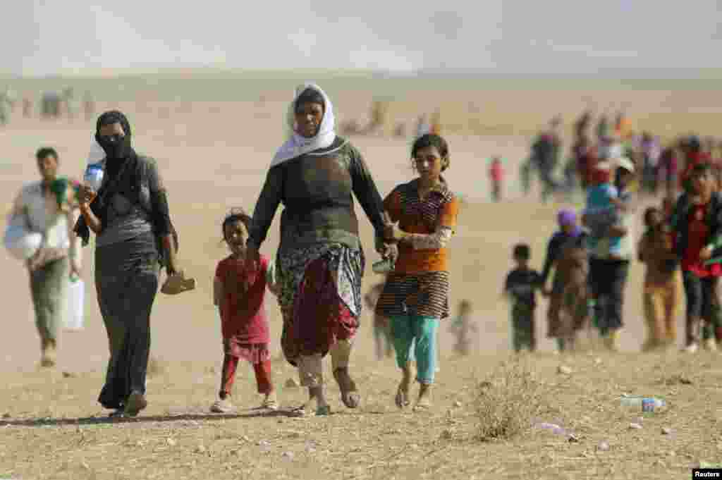 Displaced people from the minority Yazidi sect, fleeing violence from forces loyal to the Islamic State in Sinjar town, walk towards the Syrian border, on the outskirts of Sinjar mountain, near the Syrian border town of Elierbeh of Al-Hasakah Governorate 