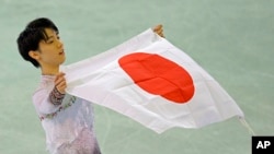 Yuzuru Hanyu of Japan poses with the national flag after he placed first in the men's free skate figure skating final following the flower ceremony at the Iceberg Skating Palace during the 2014 Winter Olympics, Feb. 14, 2014, in Sochi, Russia. 