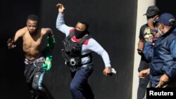 A police officer detains a suspect during a protest, as violence following the jailing of former South African President Jacob Zuma spread to the country's main economic hub in Johannesburg, South Africa, July 11, 2021. REUTERS/Sumaya Hisham
