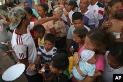 In this March 8, 2018 photo, Venezuelans wait for a free meal in Simon Bolivar Square where many are living in tents in Boa Vista, Roraima state, Brazil.