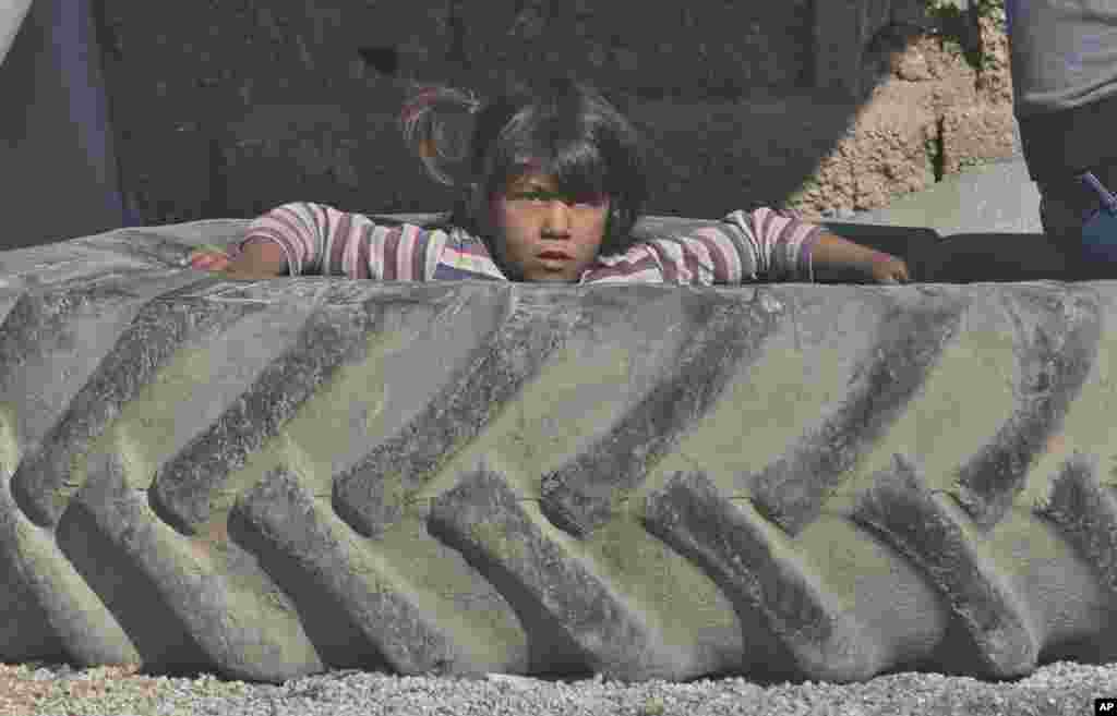 A Syrian Kurdish refugee child from the Kobani area sits inside a tractor tire at a camp in Suruc, on the Turkey-Syria border.