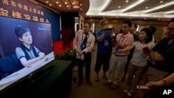 Periodistas observan el testimonio pre-grabado de Gu Kailai, esposa de Bo Xilai, en la provincia de Shandong.