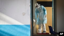 A medical worker wearing full protective equipment decontaminates a cup used by a man being quarantined after coming into contact in Uganda with a carrier of the Marburg virus, a hemorrhagic fever from the same family as Ebola, at the Kenyatta National Hospital in Nairobi, Kenya, Oct. 8, 2014. 