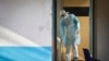 Un travailleur médical portant un équipement de protection complet décontamine une tasse utilisée par un homme mis en quarantaine après être entré en contact en Ouganda avec un porteur du virus de Marburg, au Kenya, le 8 octobre 2014 (AP/Ben Curtis)