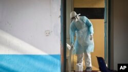 FILE - A Kenya medical worker wearing full protective equipment decontaminates a cup used by a man being quarantined after coming into contact in Uganda with a carrier of the Marburg Virus, taken Oct. 8, 2014. Now Tanzania has recorded ti first Marburg case.