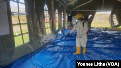 Petugas kesehatan menyemprotkan cairan disinfektan di tenda jelang pelaksanaan kegiatan psikososial di shelter Terintegrasi di Stadion Manakarra, Mamuju, Sulawesi Barat, Minggu, 31 Januari 2021. (Foto: Yoanes Litha/VOA)