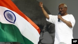 Indian social activist Anna Hazare gestures while addressing his supporters on the tenth day of his protest fast as an India's national flag flutters at the Ramlila grounds in New Delhi, August 25, 2011.